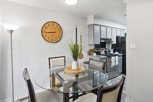 A kitchen with a table and chairs and a clock on the wall.