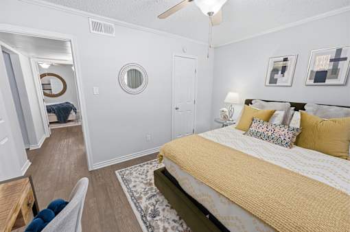 A bedroom with a bed, a chair, and a mirror.