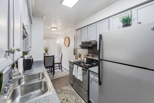 A modern kitchen with a stainless steel refrigerator, sink, and oven.
