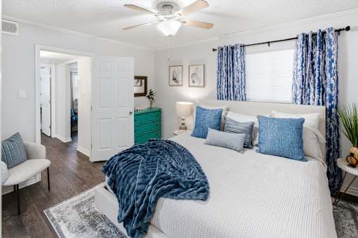 A bedroom with a bed covered in a blue blanket and a ceiling fan.