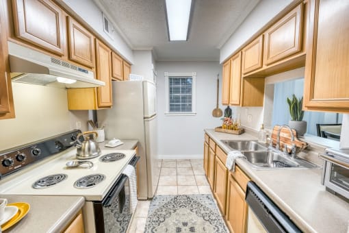 Galley kitchen with wood cabinets and electric cooktop at Le Montreaux Apartments, Austin, TX
