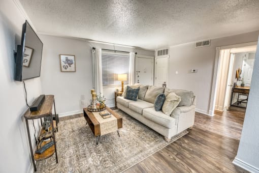 Furnished living room with sectional sofa and area rug at Le Montreaux Apartments, Austin, Texas