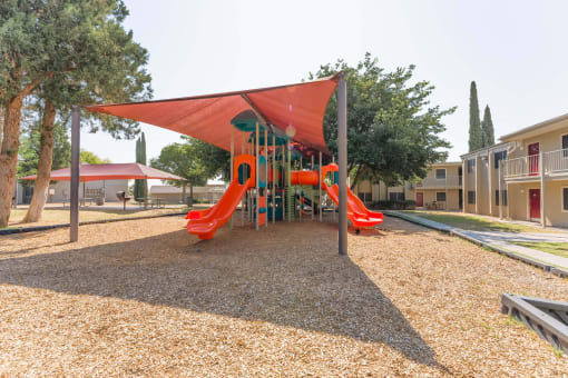 Covered playground with slides and climbing structure at Cantera Apartments, El Paso, Texas