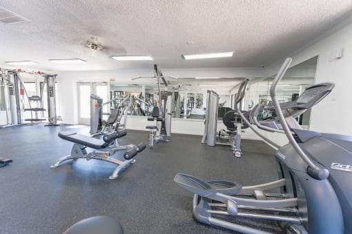 Modern fitness center with cardio machines and mirrors at Cantera Apartments, El Paso, 79935