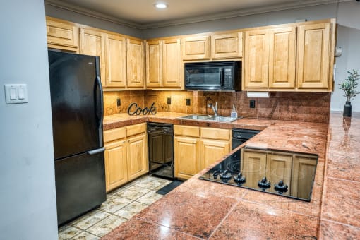 a kitchen with wooden cabinets and a black refrigerator at Le Montreaux Apartments, Austin, TX, 78759