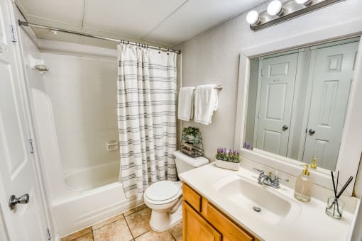Full bathroom with striped shower curtain and vanity at Le Montreaux Apartments, Austin, 78759