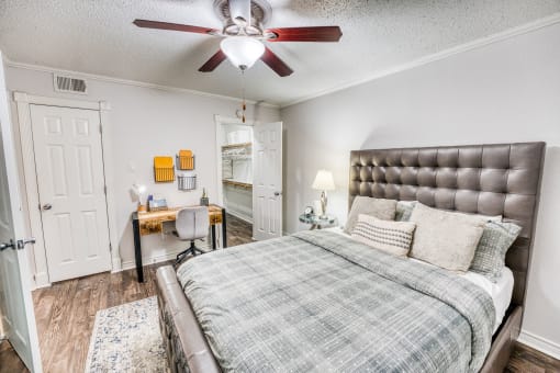 Modern bedroom with tufted headboard and ceiling fan at Le Montreaux Apartments, Texas