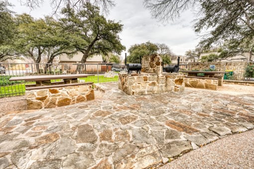 Stone outdoor grill area with picnic seating at Le Montreaux Apartments, Austin
