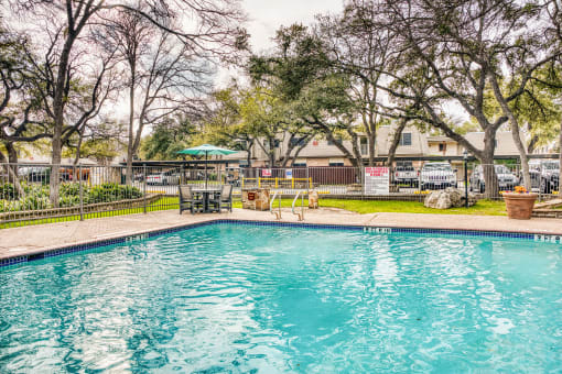 Swimming pool with patio seating and mature trees at Le Montreaux Apartments, Texas
