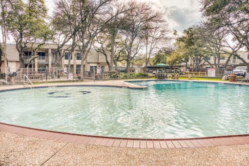 Swimming pool with brick decking and tree canopy at Le Montreaux Apartments, Austin, TX 78759
