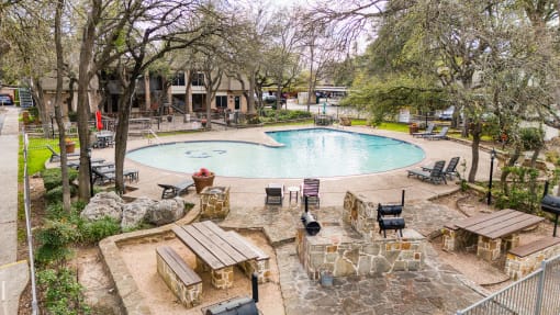Outdoor pool area with stone fire pit seating at Le Montreaux Apartments, Austin, Texas