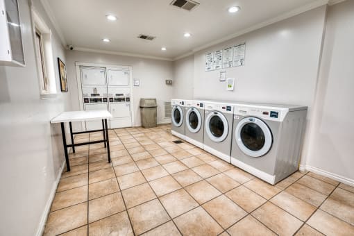 Community laundry room with front loading washers and dryers at Le Montreaux Apartments, Texas