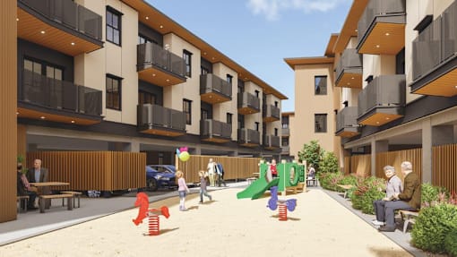 A playground area with a slide and a sandbox is located between two apartment buildings.