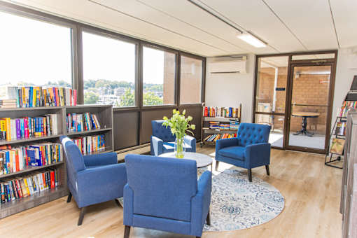 Community library with blue chairs and a table with a vase of flowers on it.