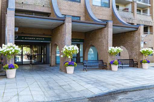 The Riverside Avenue entrance to a building with a bench and potted plants.
