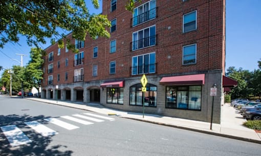 A street view of a red brick building with a yellow pedestrian crossing sign.
