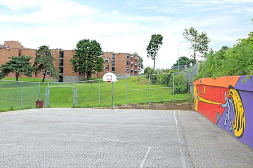 A basketball court is surrounded by a fence and a building.