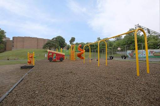 A playground with a red and yellow swing set.