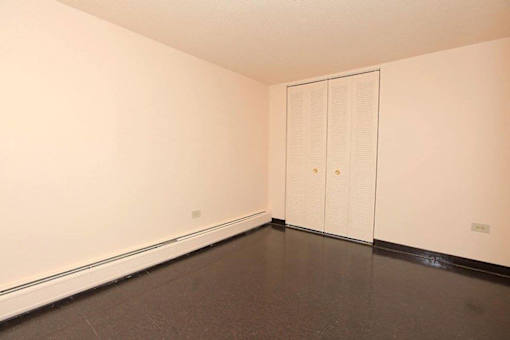 A room with a white door and a brown floor.