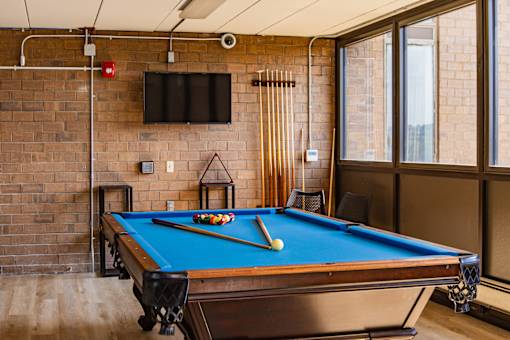 A pool table with a blue cloth and a white cue ball is in the foreground of the image.