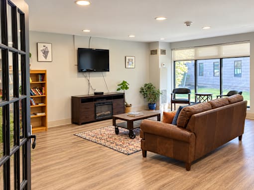 A living room with a brown couch, a television, and a bookshelf.