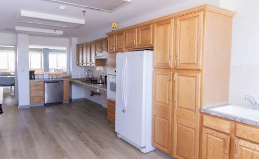 Community kitchen with wooden cabinets and a white refrigerator.
