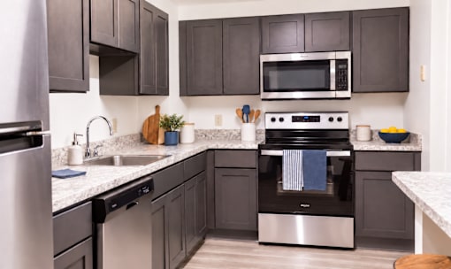 A modern kitchen with dark brown cabinets and stainless steel appliances.