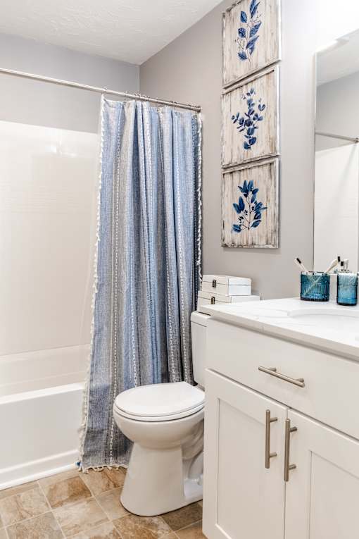 A white toilet with a blue shower curtain in the background.