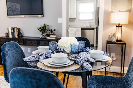 A dining table set with blue chairs and a white flower centerpiece.