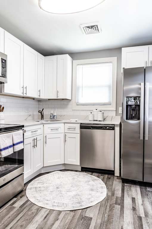 A modern kitchen with white cabinets and stainless steel appliances.