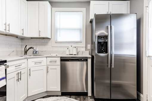 A modern kitchen with a stainless steel refrigerator and white cabinets.