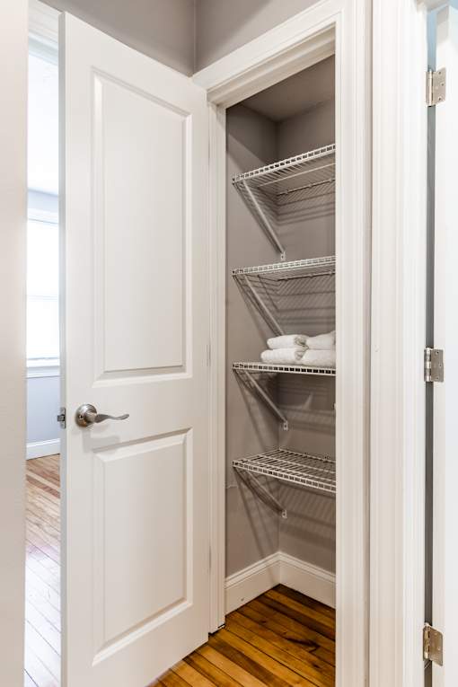 A white door is open to a pantry with shelves.