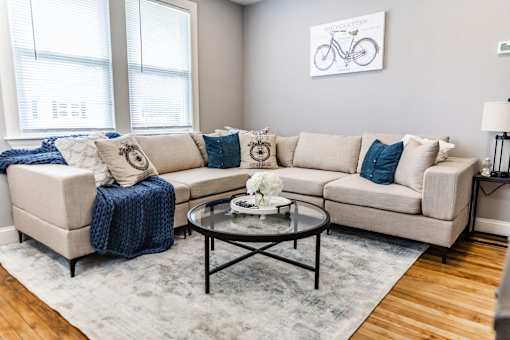 A living room with a beige couch, a coffee table, and a blue throw blanket.