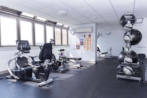 A gym with a row of stationary bikes and a row of exercise balls.