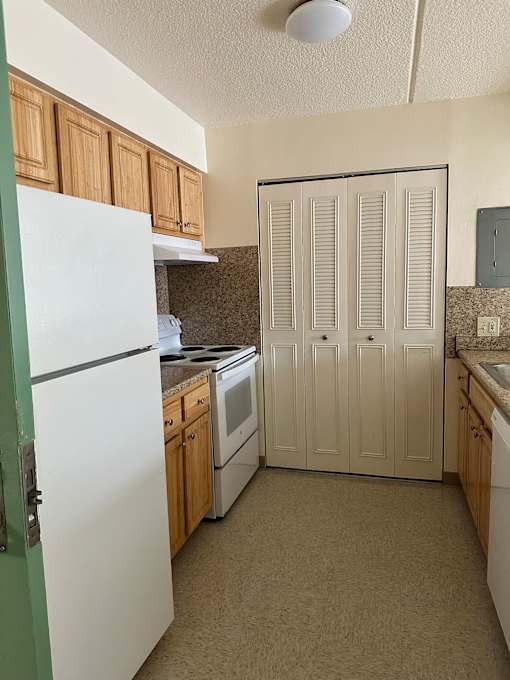 A white cabinet with drawers is mounted on a wall above a wooden table.