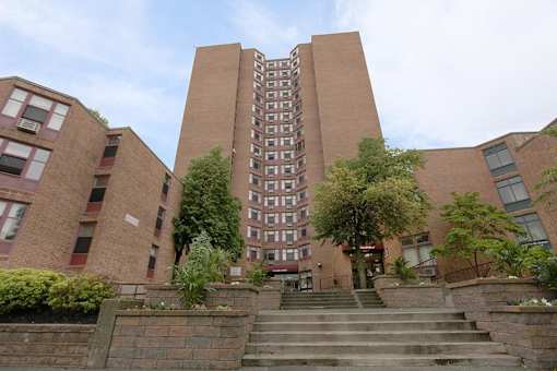A tall brick building with a staircase leading to the entrance.