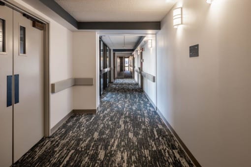 a hallway with white walls and a black and white carpet    and doors