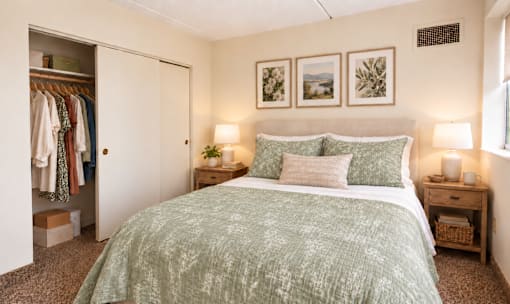 A bedroom with a bed, nightstands, and a closet.