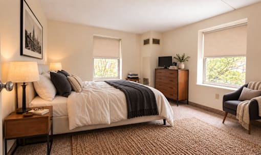 A bedroom with a large bed, a chair, and a window.