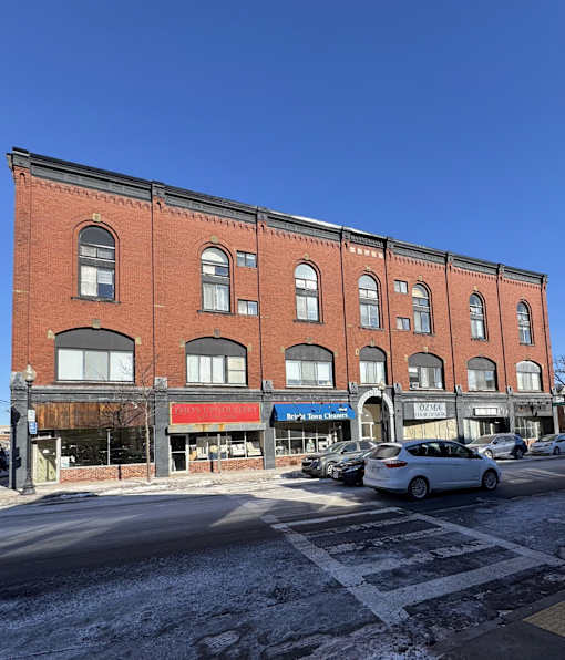 A red brick building with a white car parked in front of it.