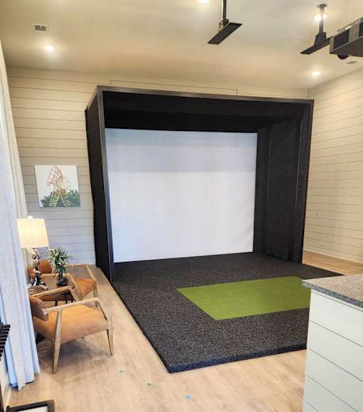 A room with a black screen and a green rug.