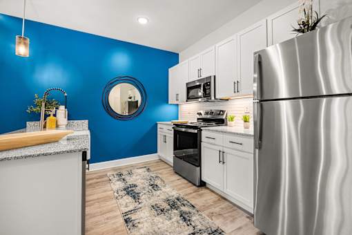 Modern kitchen with white cabinets and blue accent wall at Ardmore at Prosperity Apartments, Tennessee