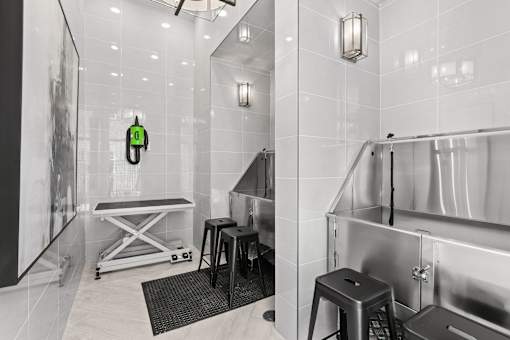 A bathroom with a white tiled wall and a black and white photo on the wall.
