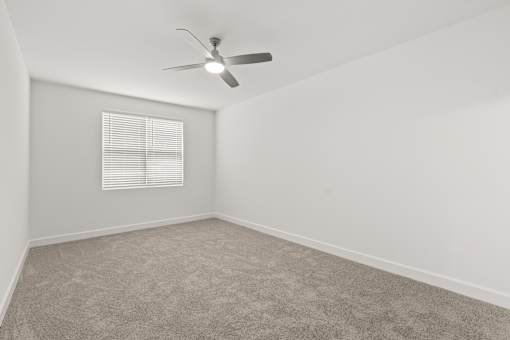 A room with a ceiling fan and a window with blinds.