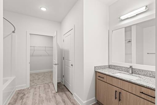 A bathroom with a sink, mirror, and wooden floors.