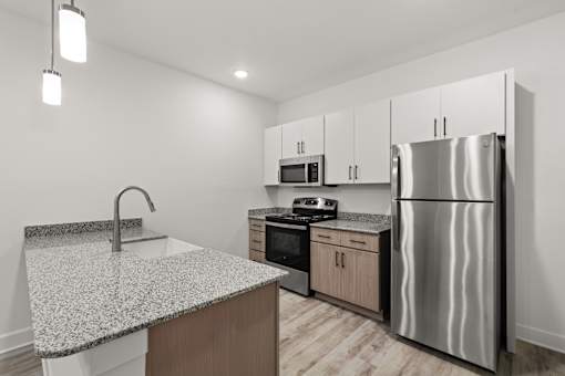 A modern kitchen with a granite countertop and stainless steel appliances.