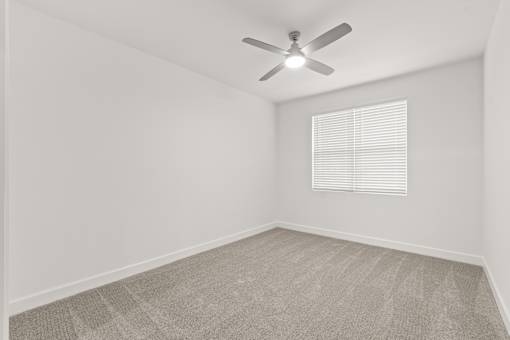A room with a ceiling fan and a window with blinds.