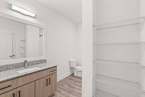 A white bathroom with a sink, mirror, and toilet.