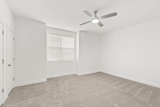 A room with a ceiling fan and carpeted floor.