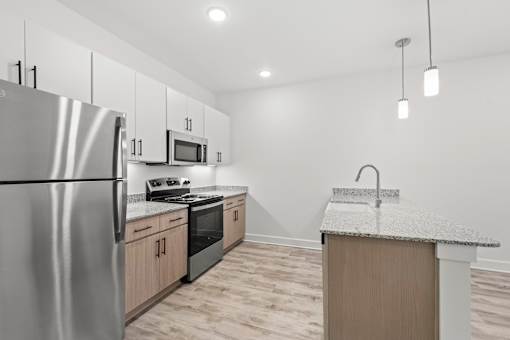A kitchen with a stainless steel refrigerator, microwave, oven, and sink.